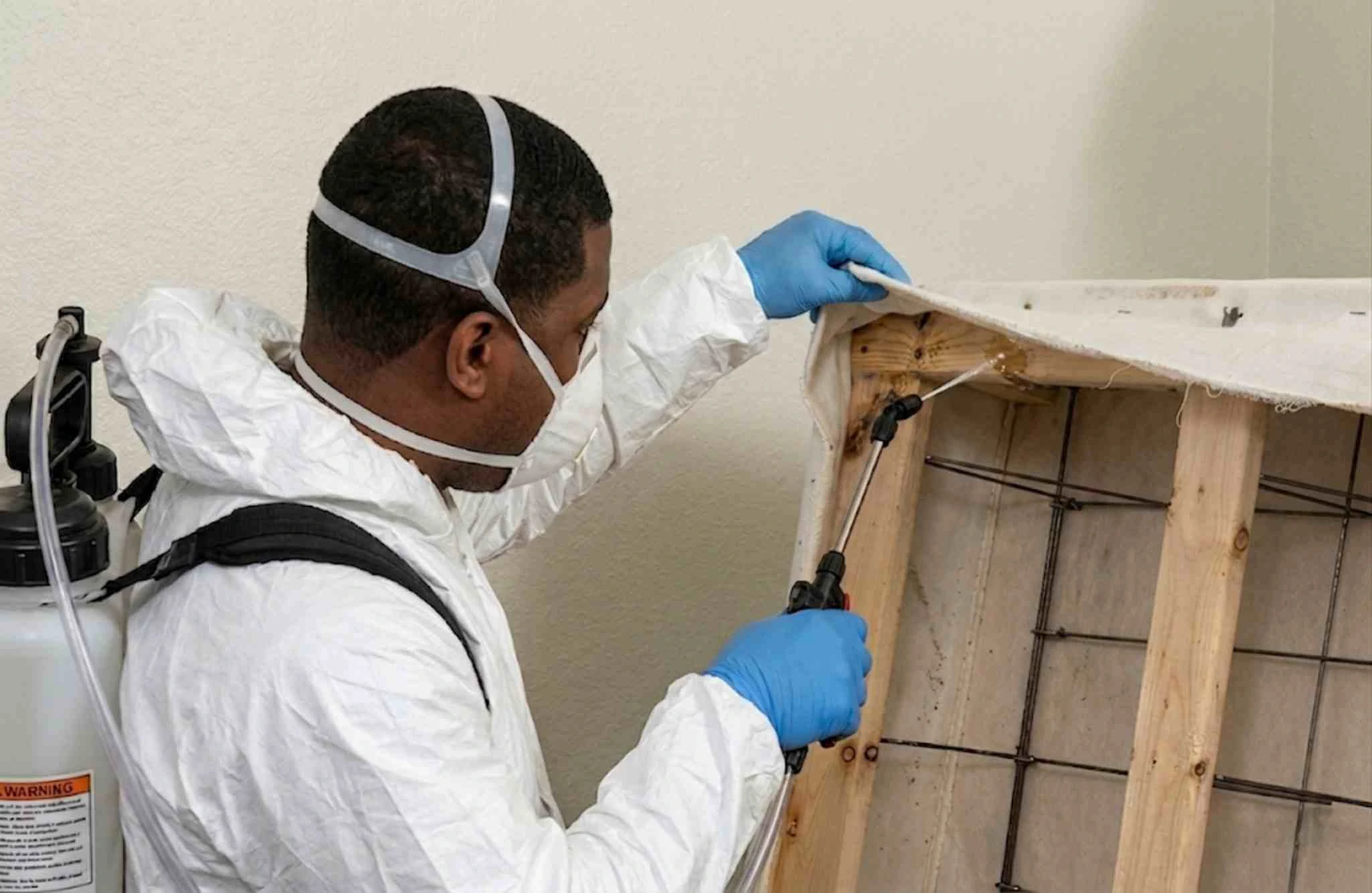 Professional pest control technician applying spray treatment to bed frame for bed bugs in Bloomington, Indiana